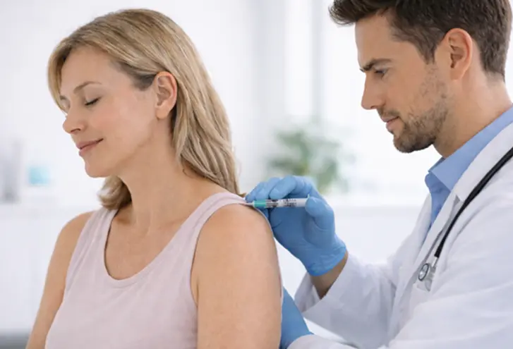 Doctor administering shoulder injection to patient as part of thoracic outlet syndrome treatment